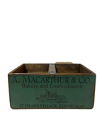 Vintage wooden box with 'A. Macarthur & Co.' branding on a light wooden floor.